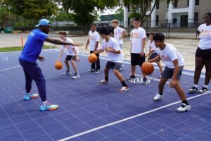JAYLEN WHITE DEMONSTRATES PROPER DRIBBLING TECHNIQUES DURING A BASKETBALL CLINIC ON THE NEW DREAM COURT AT PARK MEADOWS COMMUNITY CLUB