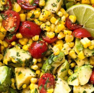 Fresh corn and avocado salad with cherry tomatoes and a lime wedge