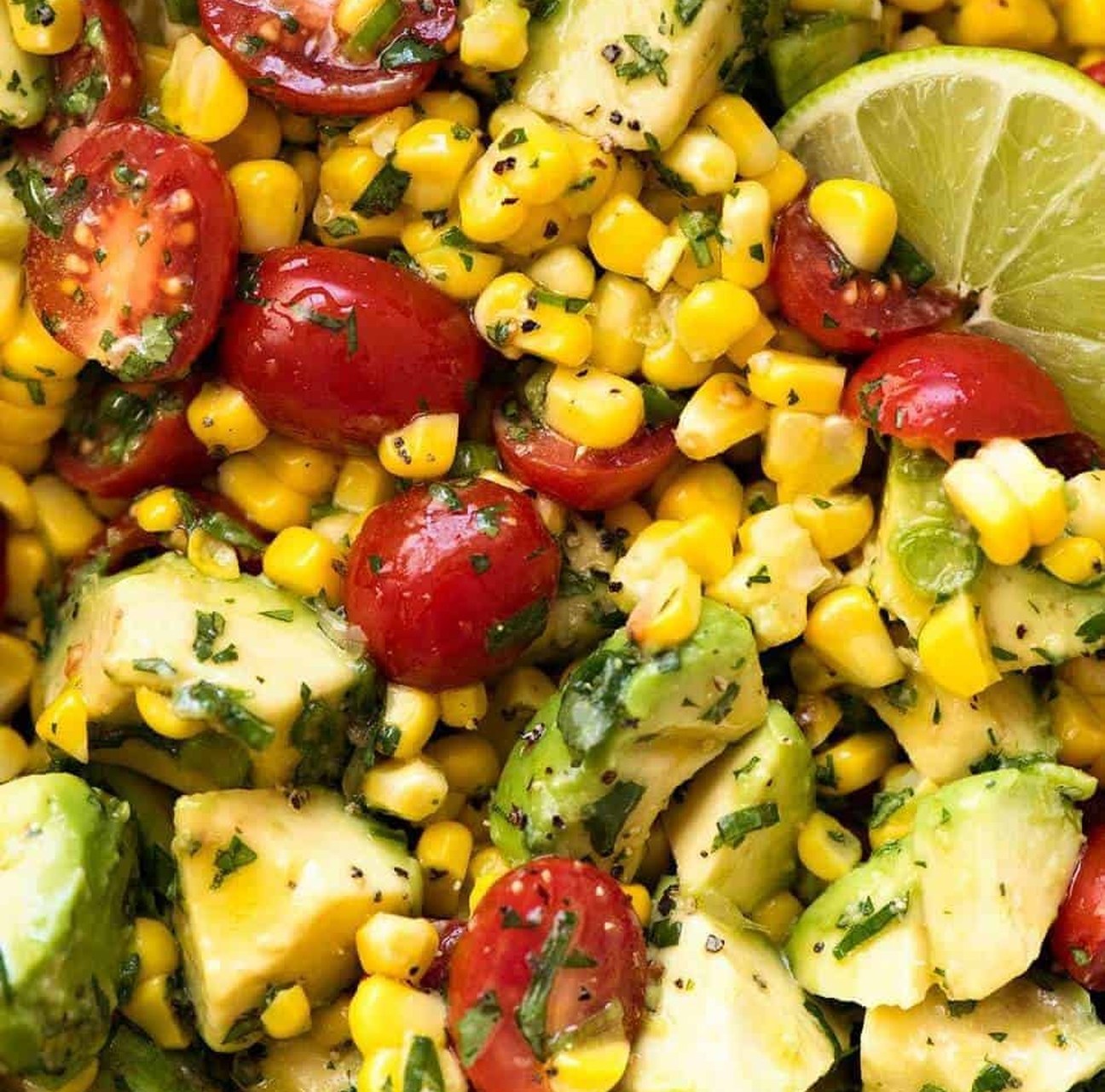 Fresh corn and avocado salad with cherry tomatoes and a lime wedge
