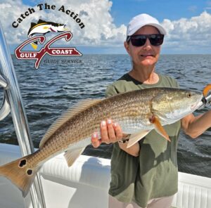 Angler on a boat holding a redfish caught in Gulf Coast waters