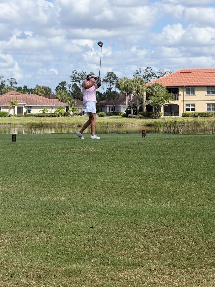 Golfer following through on a tee shot beside a pond