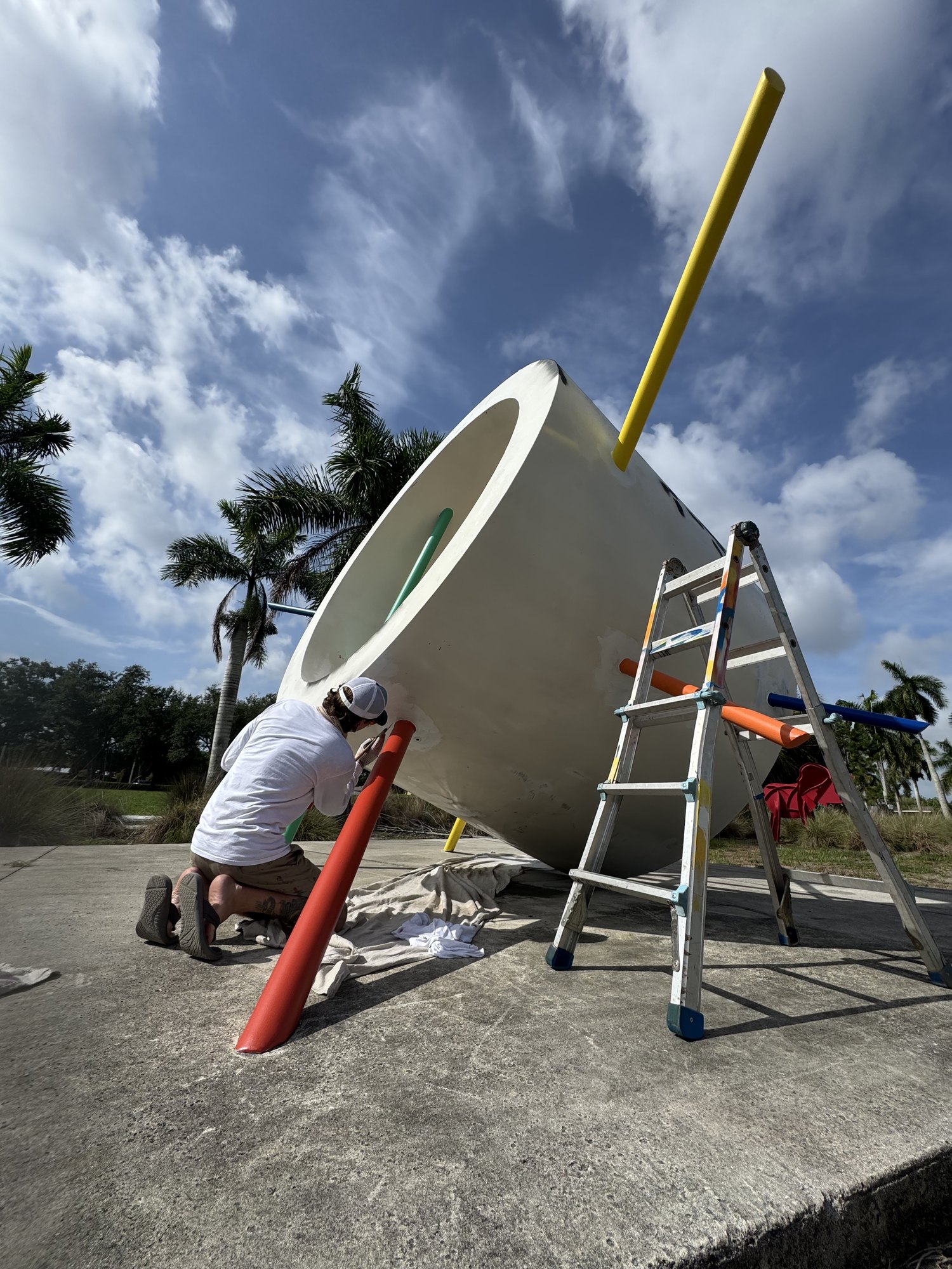 Jason Sanders kneeling to refinish the You Are Here sculpture