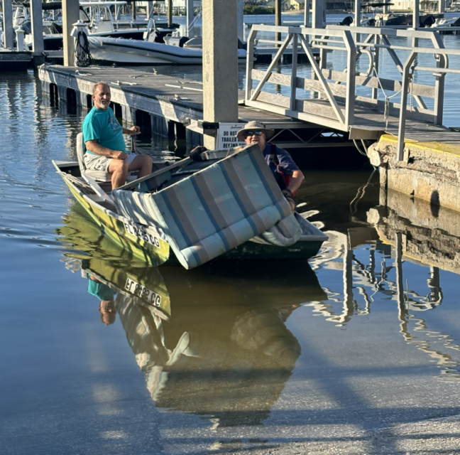 Volunteers hauling a discarded sleeper sofa from Estero Bay onto a boat ramp