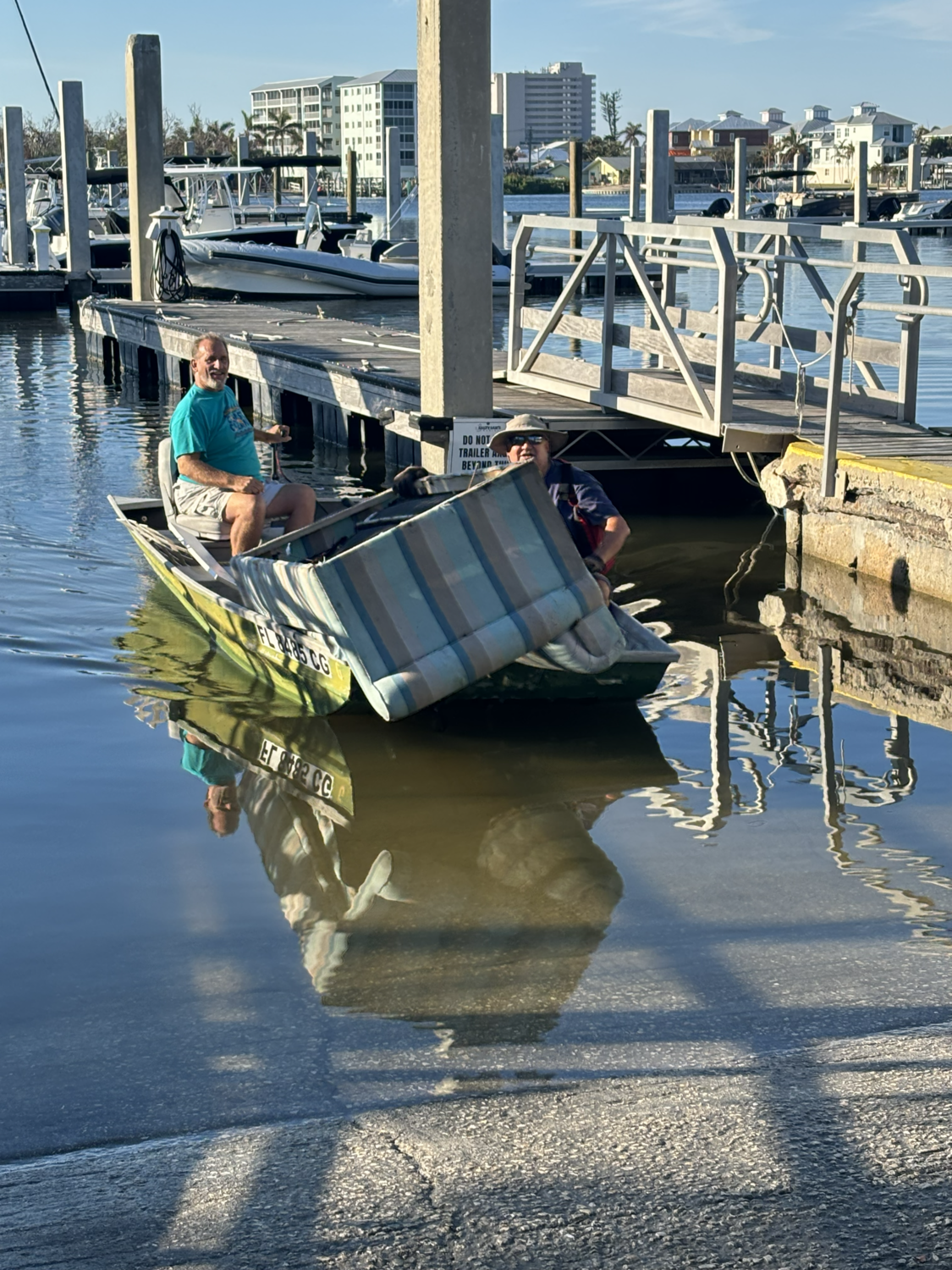 Volunteers hauling a discarded sleeper sofa from Estero Bay onto a boat ramp