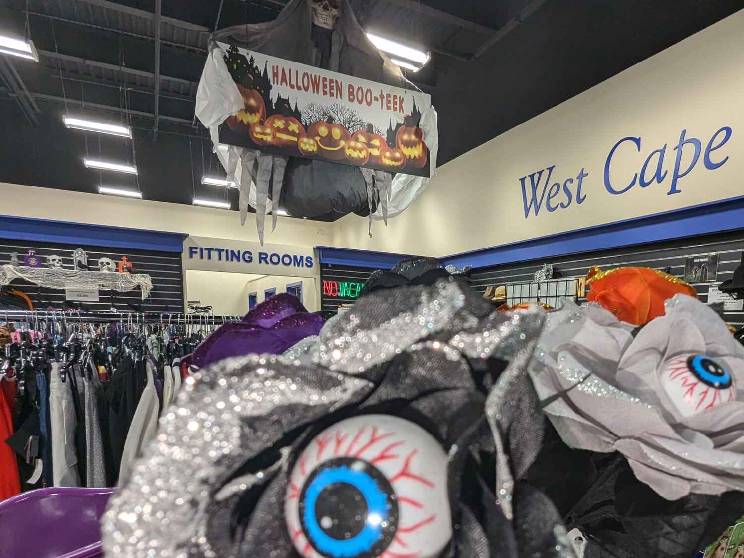 Halloween Boo-teek banner above costume racks and eyeball masks at Goodwill