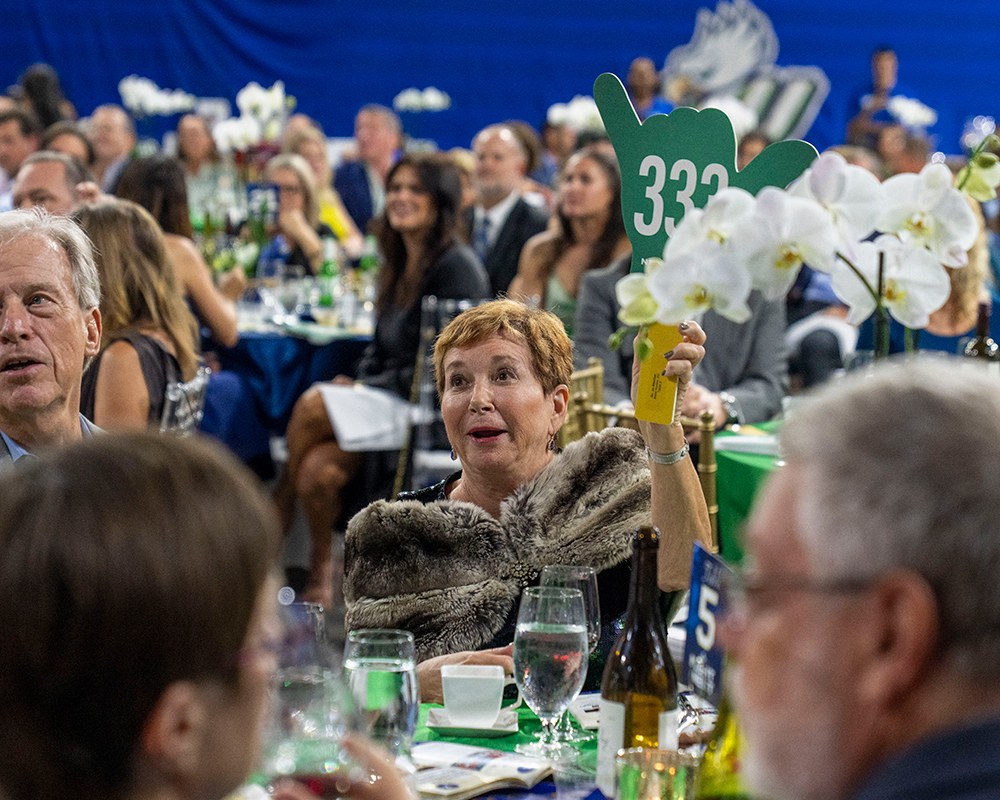 Guest raises bid paddle 333 during the auction at FGCU's Night at the Nest Gala