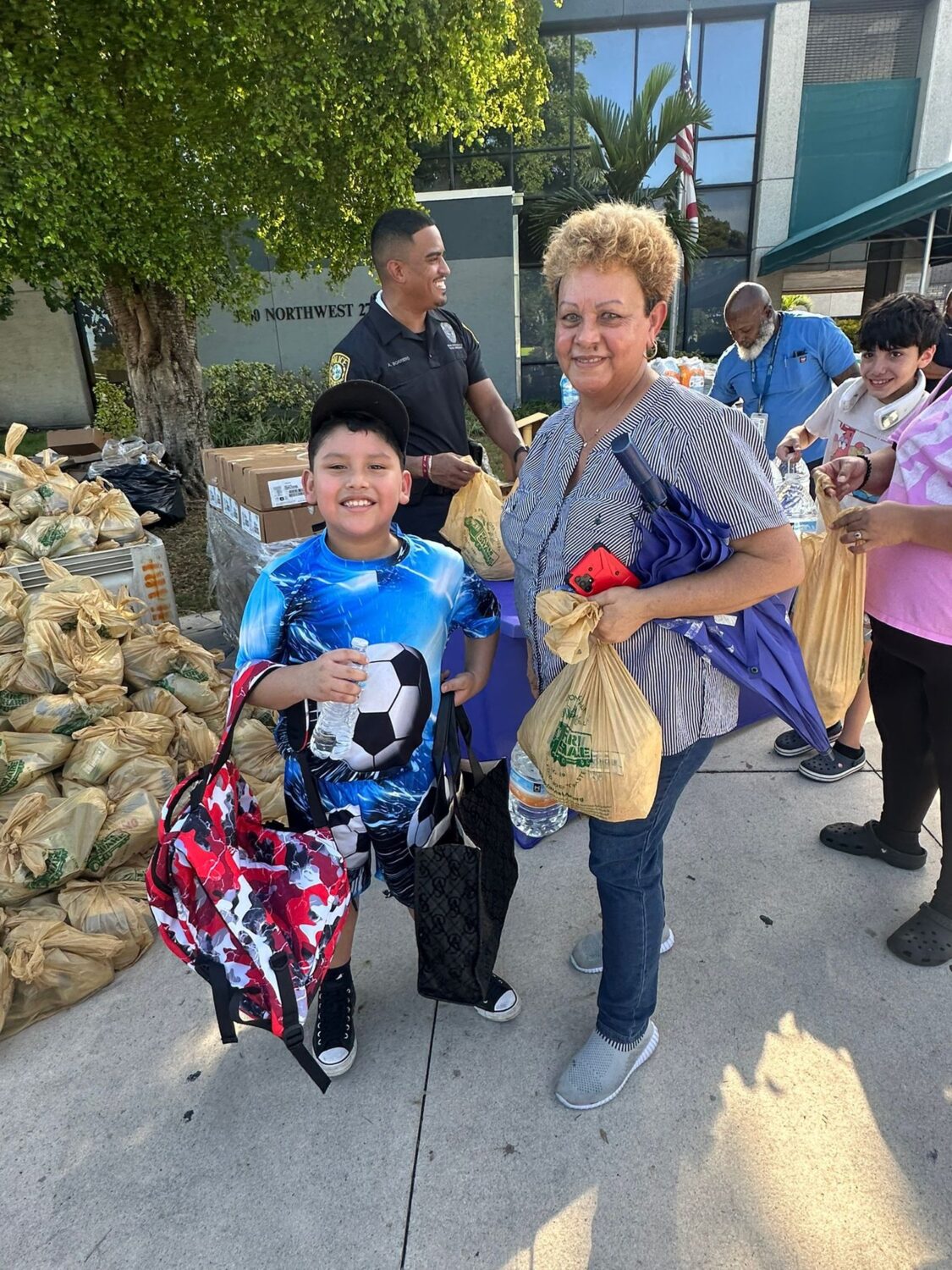 Woman and boy carrying food bags and backpacks at a Farm Share distribution