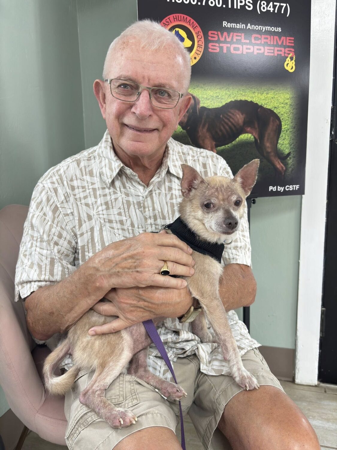 Smiling man holding a small tan chihuahua at Gulf Coast Humane Society