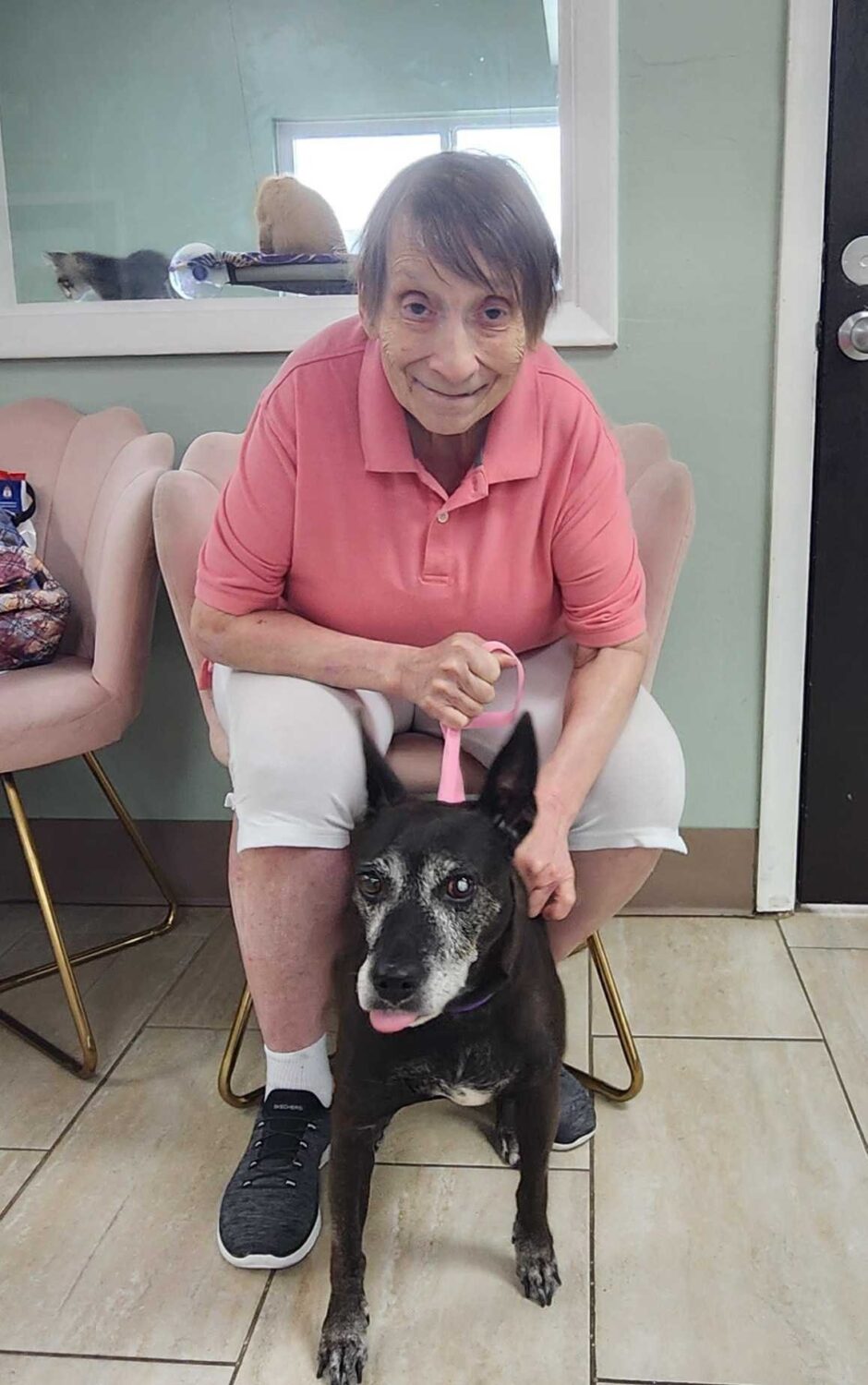 Woman seated with a black dog on a leash at the shelter