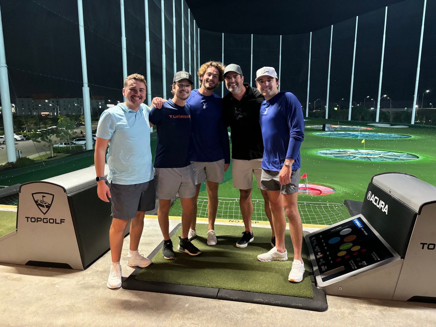 Five friends arm in arm at a Topgolf bay during the KLCB fundraiser
