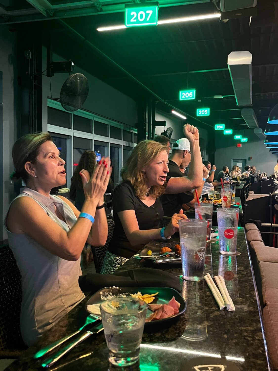 Guests cheering at a Topgolf bay during the KLCB fundraiser