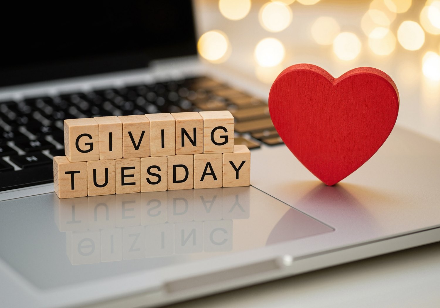 Giving Tuesday spelled in wooden blocks beside a red heart on a laptop